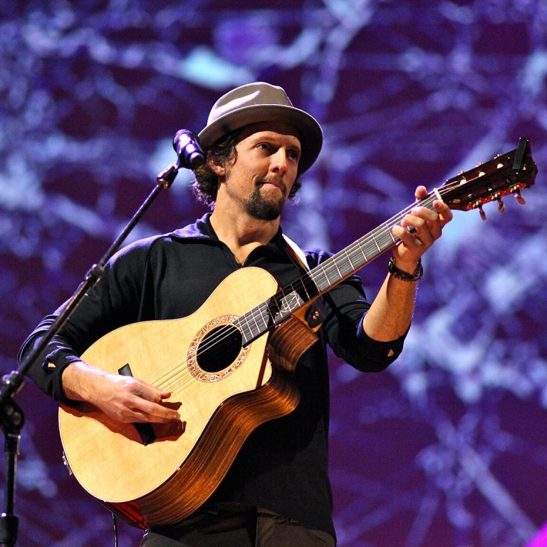 Jason Mraz performing at a concert playing guitar